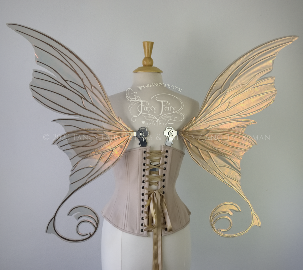 Back view of an ivory dress form wearing an alabaster underbust corset and large rose gold iridescent fairy wings with lots of intricate silver veins, some have 'thorns'. Upper panels curve slightly downwards along top edge with pointy tips, bottom panels have tails