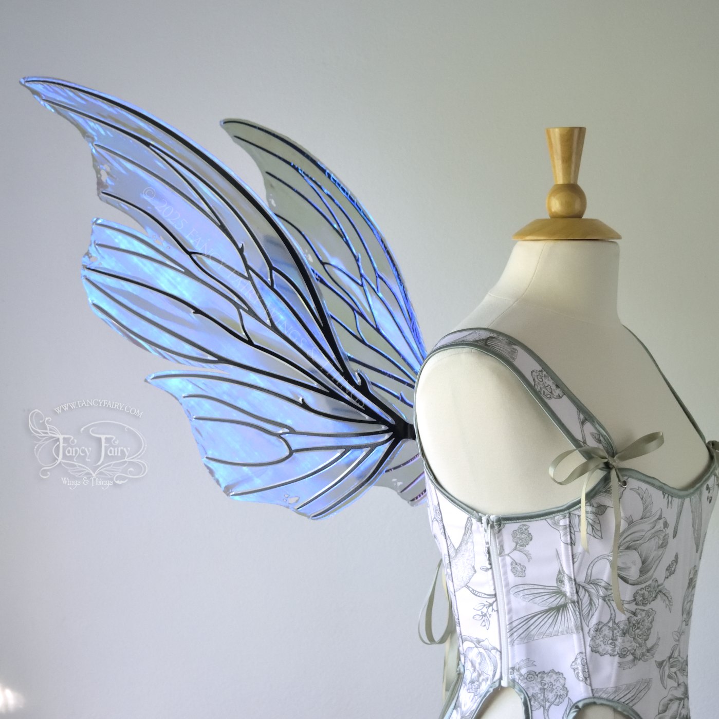 Left side view of an ivory dress form wearing large violet iridescent fairy wings with lots of intricate black veins, some have 'thorns'