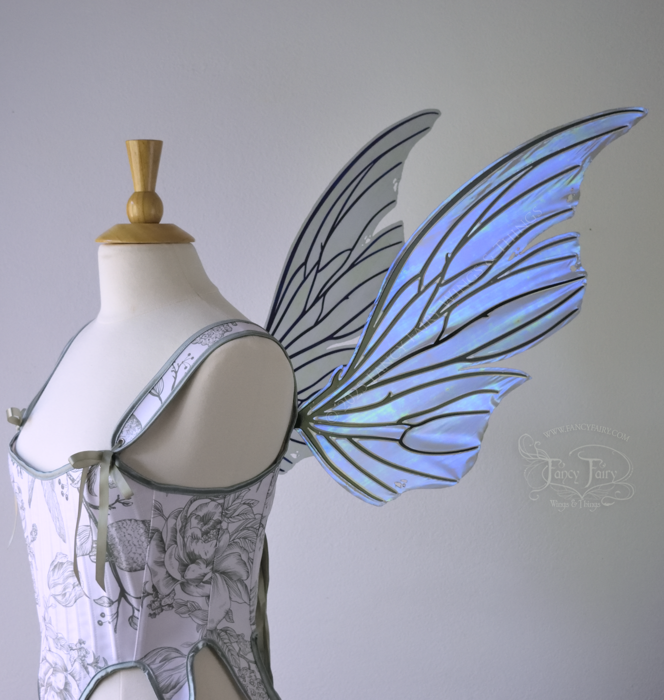 Right side view of an ivory dress form wearing large violet iridescent fairy wings with lots of intricate black veins, some have 'thorns'