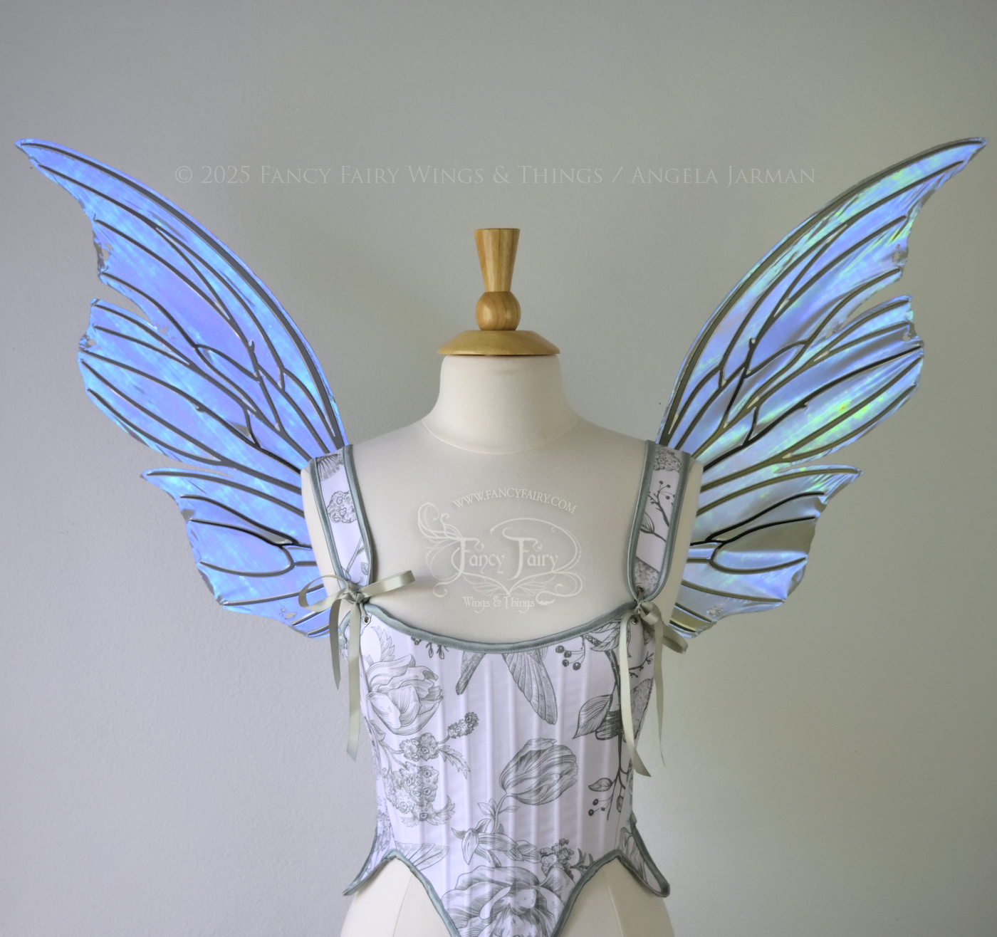Front view of an ivory dress form wearing large violet iridescent fairy wings with lots of intricate black veins, some have 'thorns'