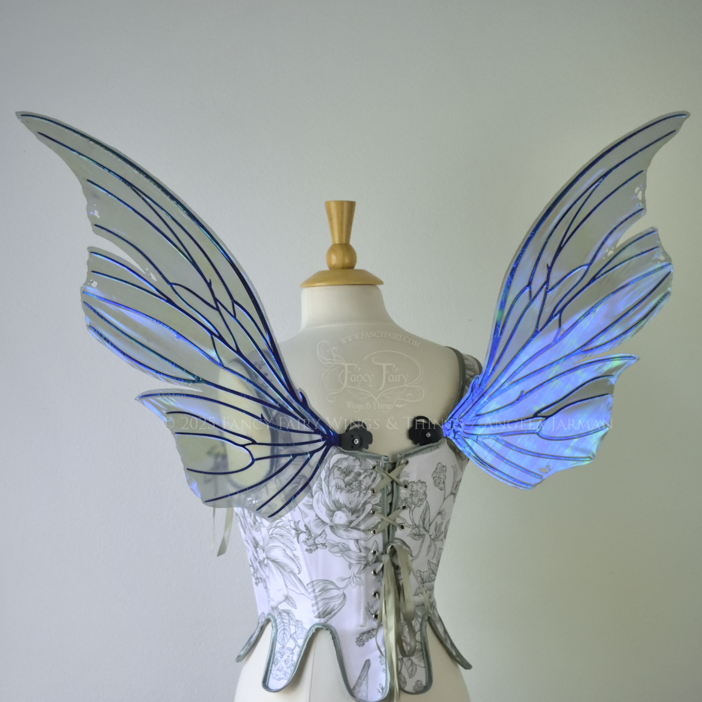 Back view of an ivory dress form wearing large violet iridescent fairy wings with lots of intricate black veins, some have 'thorns'