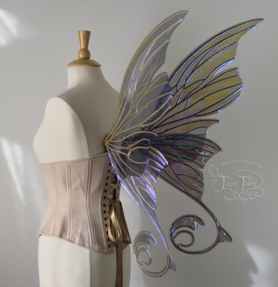 Back 3/4 view of an ivory dress form wearing an alabaster underbust corset and large grey transparent fairy wings with lots of intricate gold veins, some have 'thorns'. Upper panels curve slightly downwards along top edge with pointy tips, bottom panels have tails