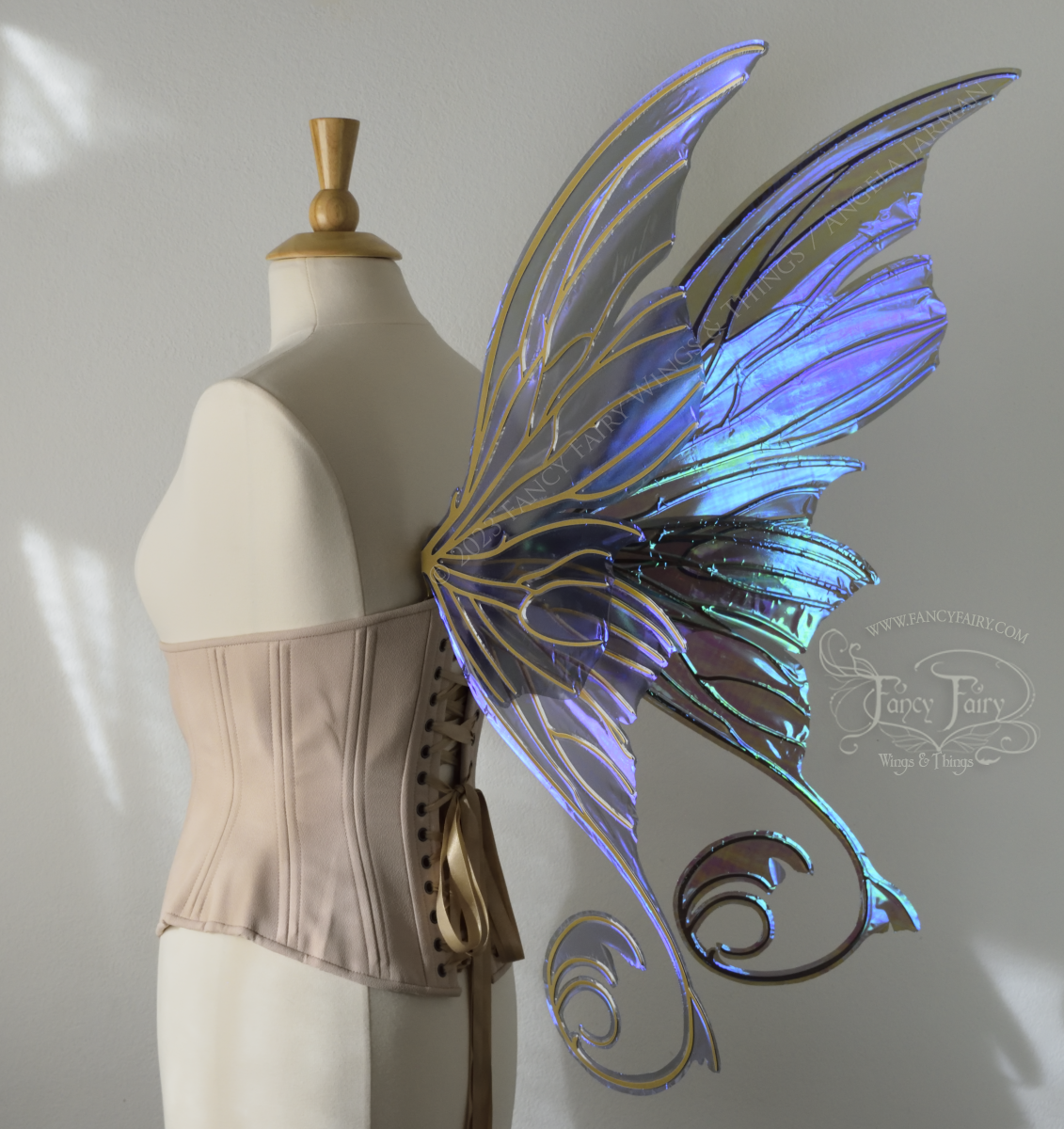 Back 3/4 view of an ivory dress form wearing an alabaster underbust corset and large purple iridescent fairy wings with lots of intricate gold veins, some have 'thorns'. Upper panels curve slightly downwards along top edge with pointy tips, bottom panels have tails