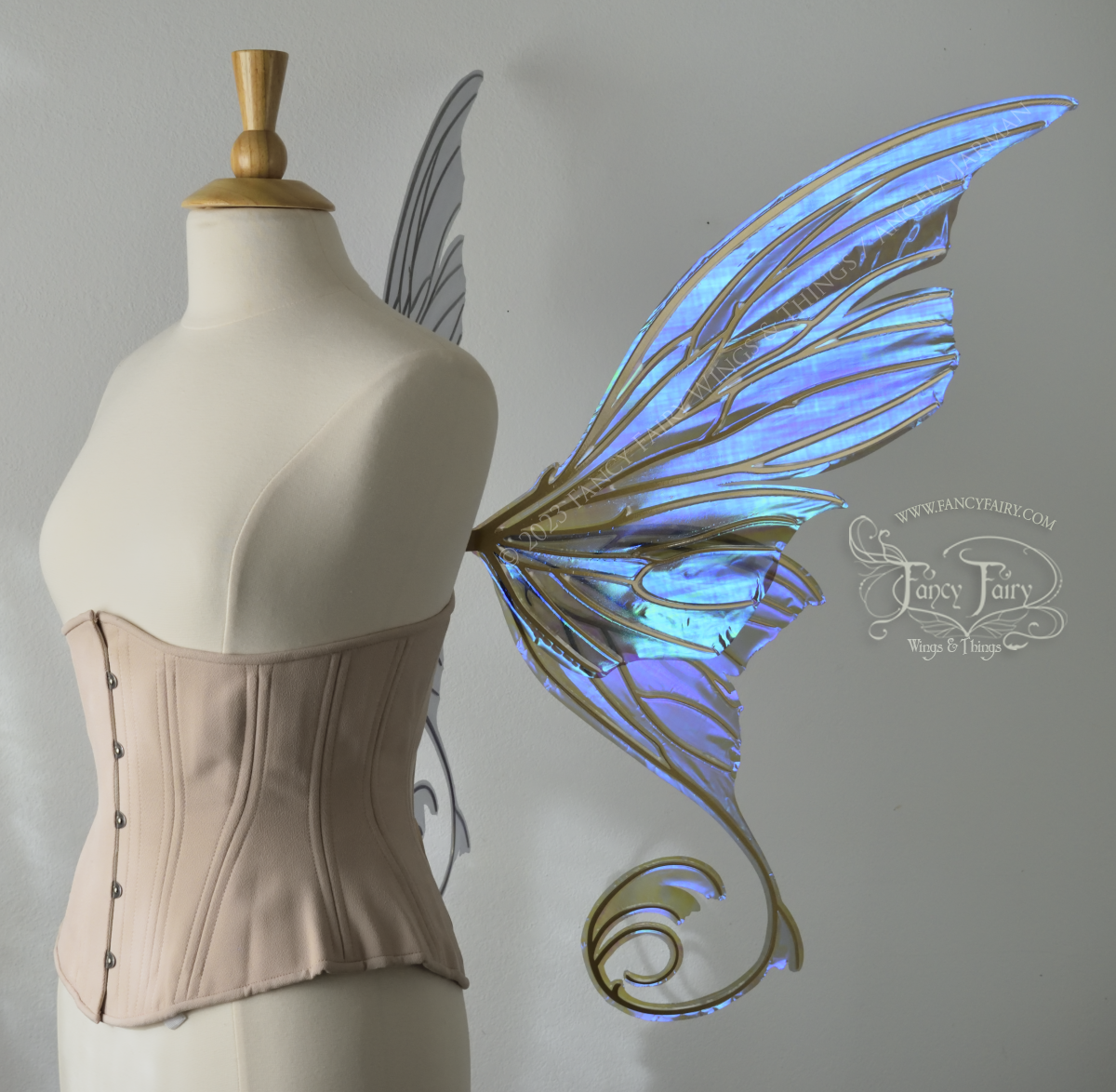 Right side view of an ivory dress form wearing an alabaster underbust corset and large purple iridescent fairy wings with lots of intricate gold veins, some have 'thorns'. Upper panels curve slightly downwards along top edge with pointy tips, bottom panels have tails