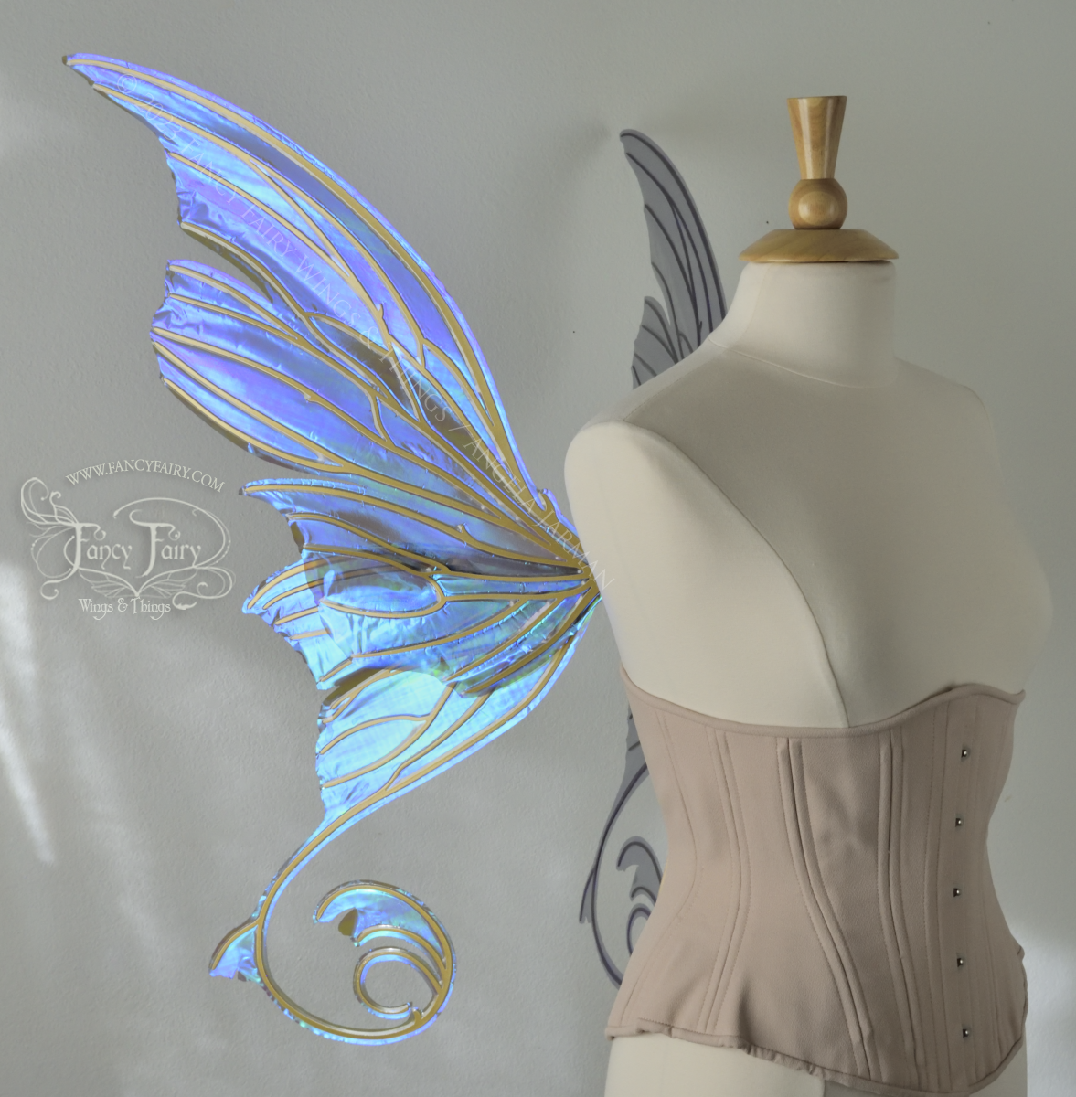 Left side view of an ivory dress form wearing an alabaster underbust corset and large purple iridescent fairy wings with lots of intricate gold veins, some have 'thorns'. Upper panels curve slightly downwards along top edge with pointy tips, bottom panels have tails