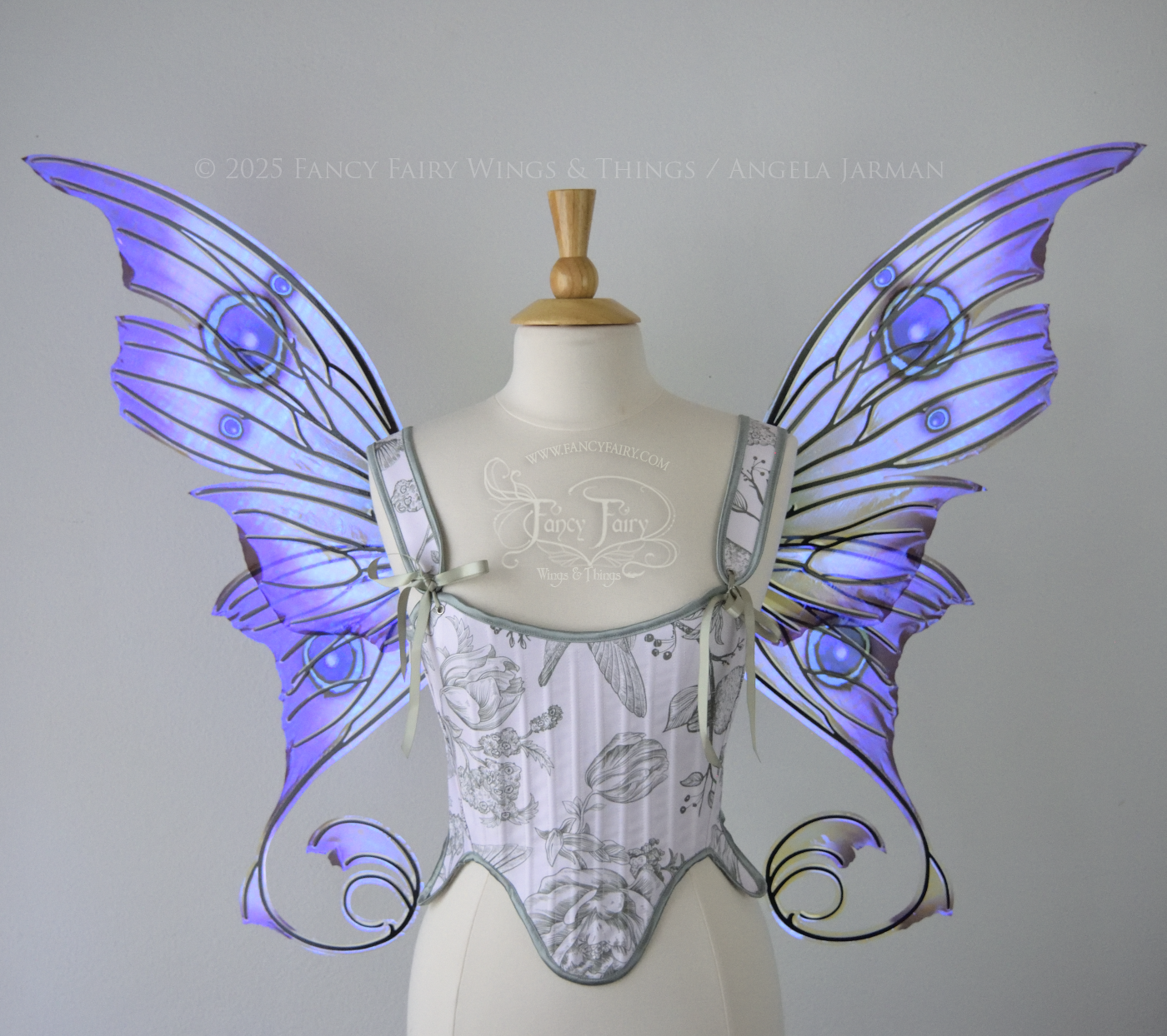 Large purple, teal & green iridescent fairy wings with thorny black veins The upper panels curve slightly downwards along the top edge with pointy tips, the bottom panels have tails that curve inward toward the body. Worn on a dress form, front view