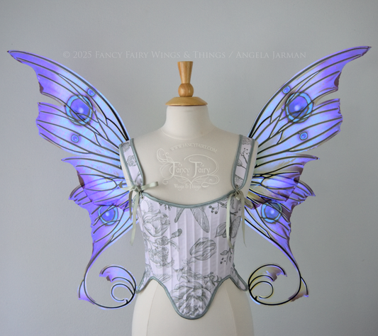 Large purple, teal & green iridescent fairy wings with thorny black veins The upper panels curve slightly downwards along the top edge with pointy tips, the bottom panels have tails that curve inward toward the body. Worn on a dress form, front view