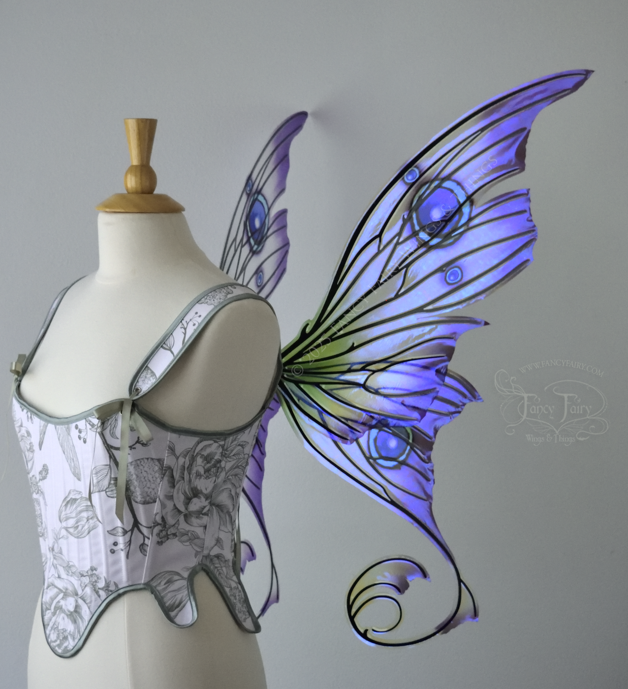 Large purple, teal & green iridescent fairy wings with thorny black veins The upper panels curve slightly downwards along the top edge with pointy tips, the bottom panels have tails that curve inward toward the body. Worn on a dress form, right side view
