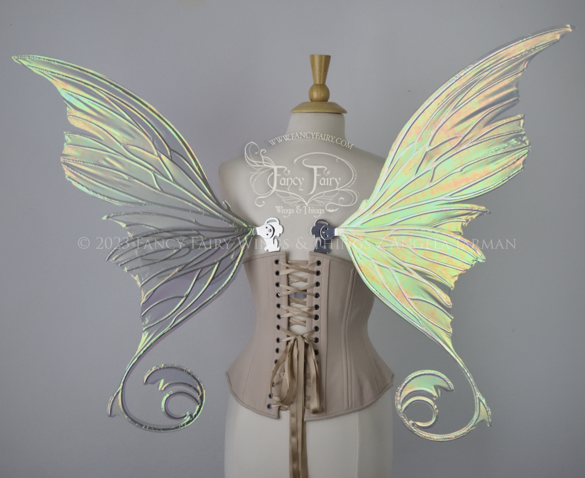 Back view of an ivory dress form wearing an alabaster underbust corset and large rose gold iridescent fairy wings with lots of intricate silver veins, some have 'thorns'. Upper panels curve slightly downwards along top edge with pointy tips, bottom panels have tails
