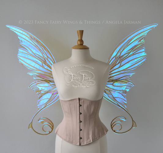 Front view of a dress form wearing an underbust corset & large blue iridescent fairy wings with lots of intricate veins, some have 'thorns'. Upper panels curve slightly downwards along top edge with pointy tips, bottom panels have tails