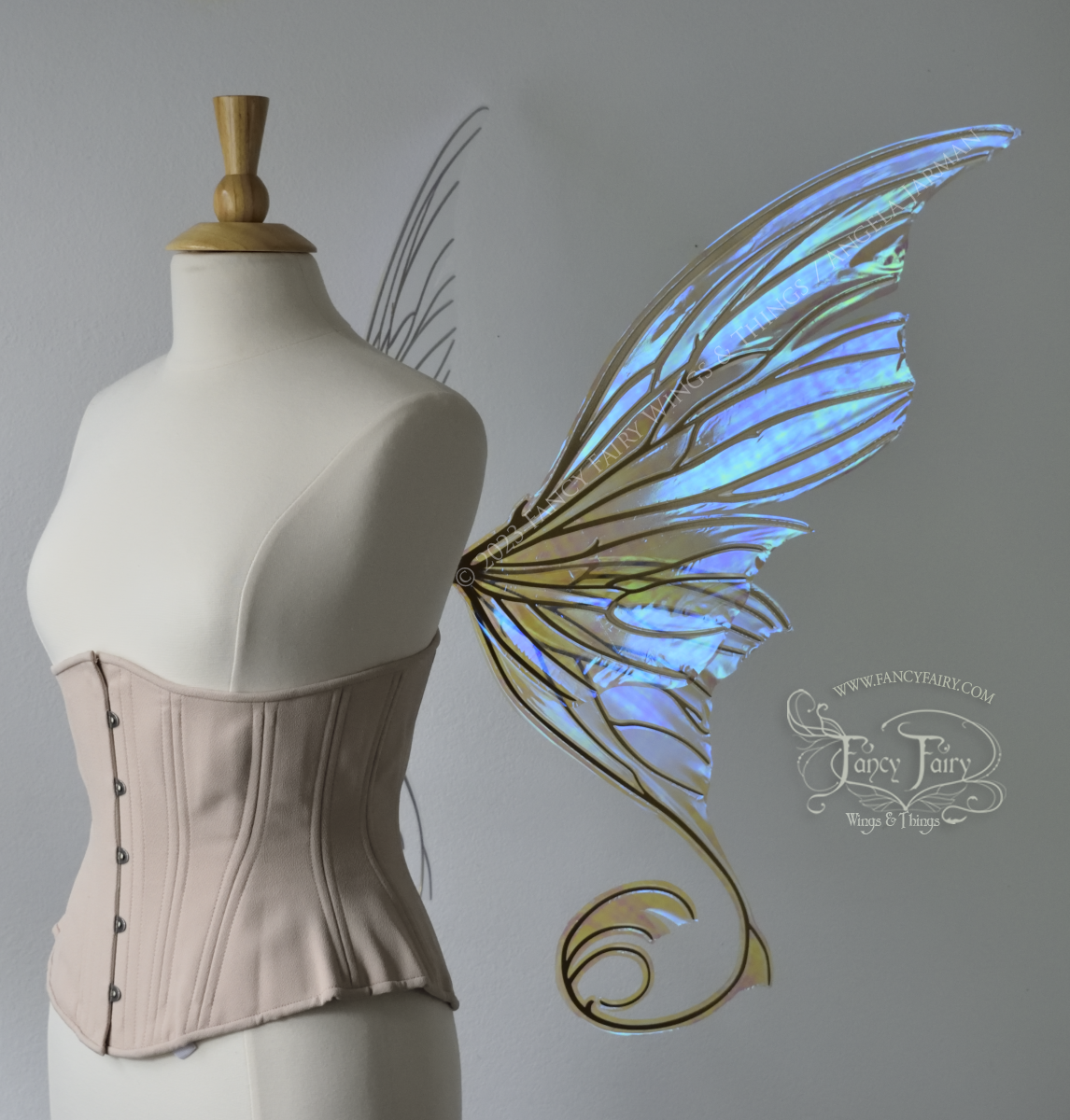 Right side view of a dress form wearing an underbust corset & large blue iridescent fairy wings with lots of intricate veins, some have 'thorns'. Upper panels curve slightly downwards along top edge with pointy tips, bottom panels have tails