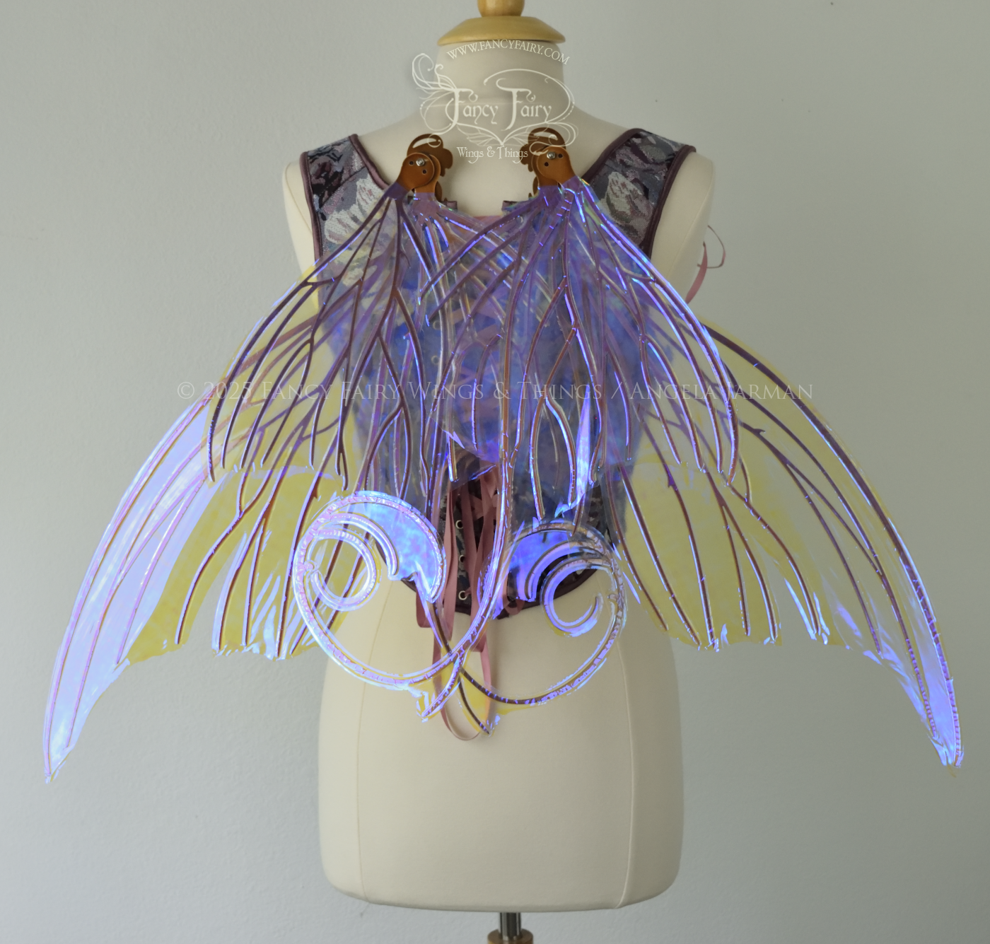 Back view of an ivory dress form wearing large clear violet iridescent fairy wings with lots of intricate copper veins, some have 'thorns'. Upper panels curve slightly downwards along top edge with pointy tips, bottom panels have tails, wings are in resting position