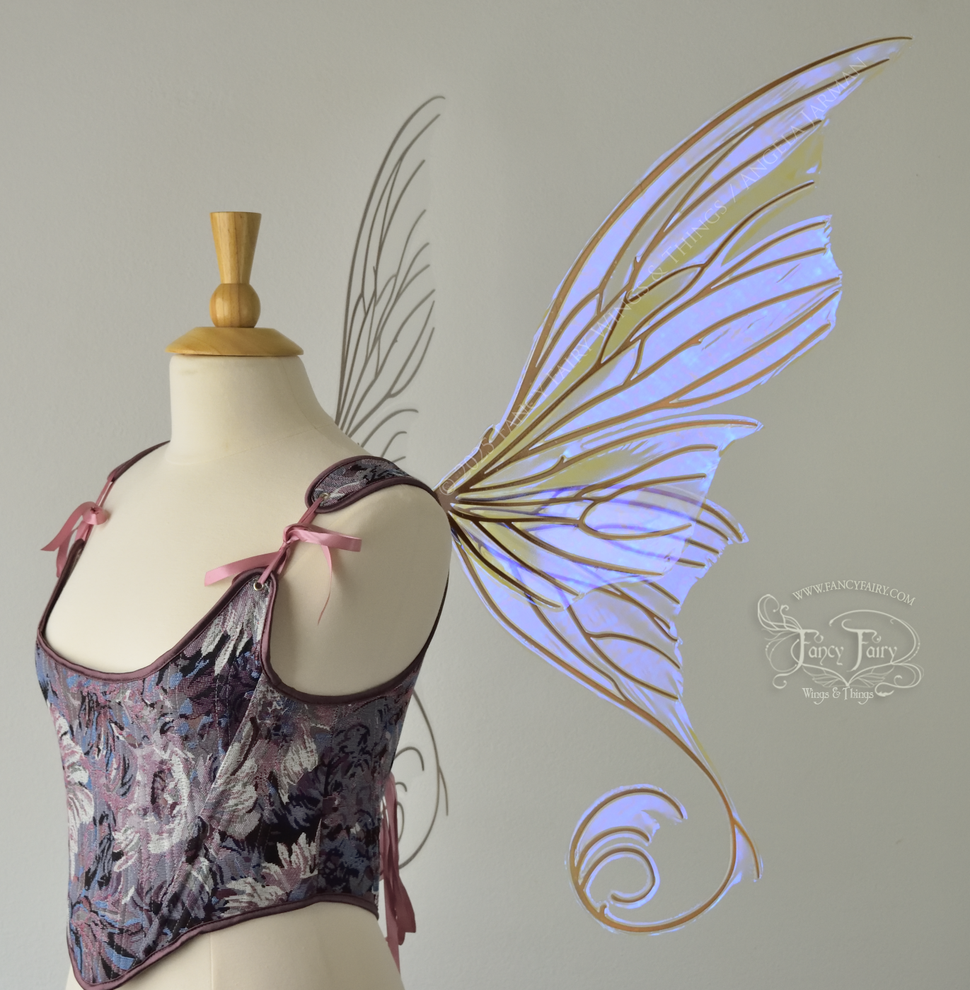 Right side view of an ivory dress form wearing large clear violet iridescent fairy wings with lots of intricate copper veins, some have 'thorns'. Upper panels curve slightly downwards along top edge with pointy tips, bottom panels have tails