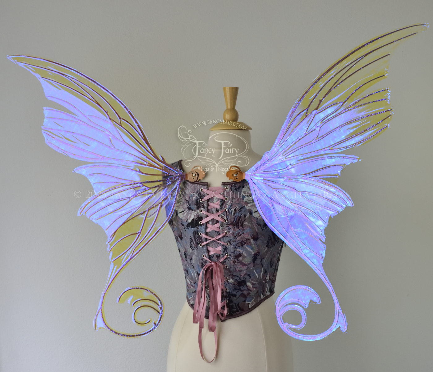 Back view of an ivory dress form wearing large clear violet iridescent fairy wings with lots of intricate copper veins, some have 'thorns'. Upper panels curve slightly downwards along top edge with pointy tips, bottom panels have tails