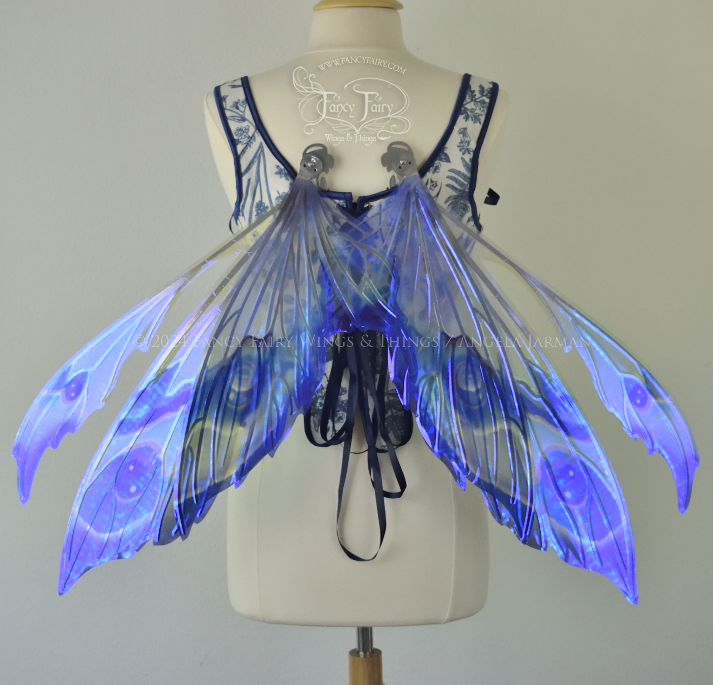 Large iridescent blue & purple painted fairy wings with pointed tips & antennae, with silver veins, worn on a dress form, back view, in resting position.