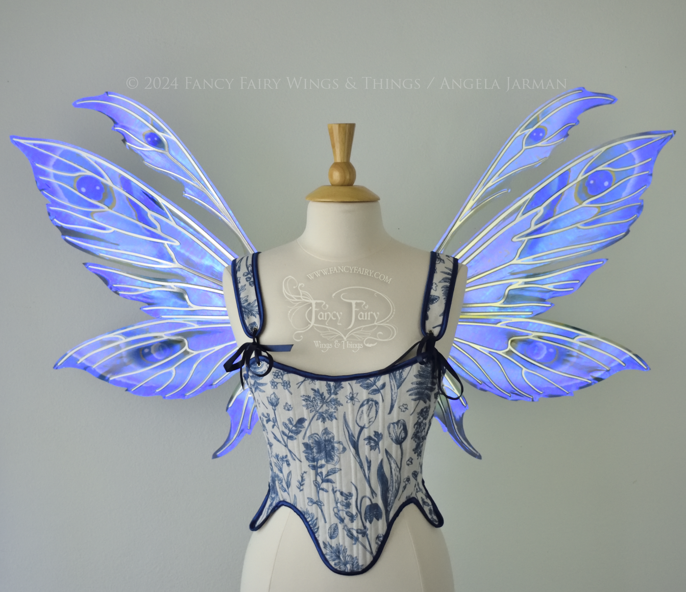 Large iridescent blue & purple painted fairy wings with pointed tips & antennae, with silver veins, worn on a dress form, front view.