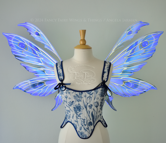 Large iridescent blue & purple painted fairy wings with pointed tips & antennae, with silver veins, worn on a dress form, front view.