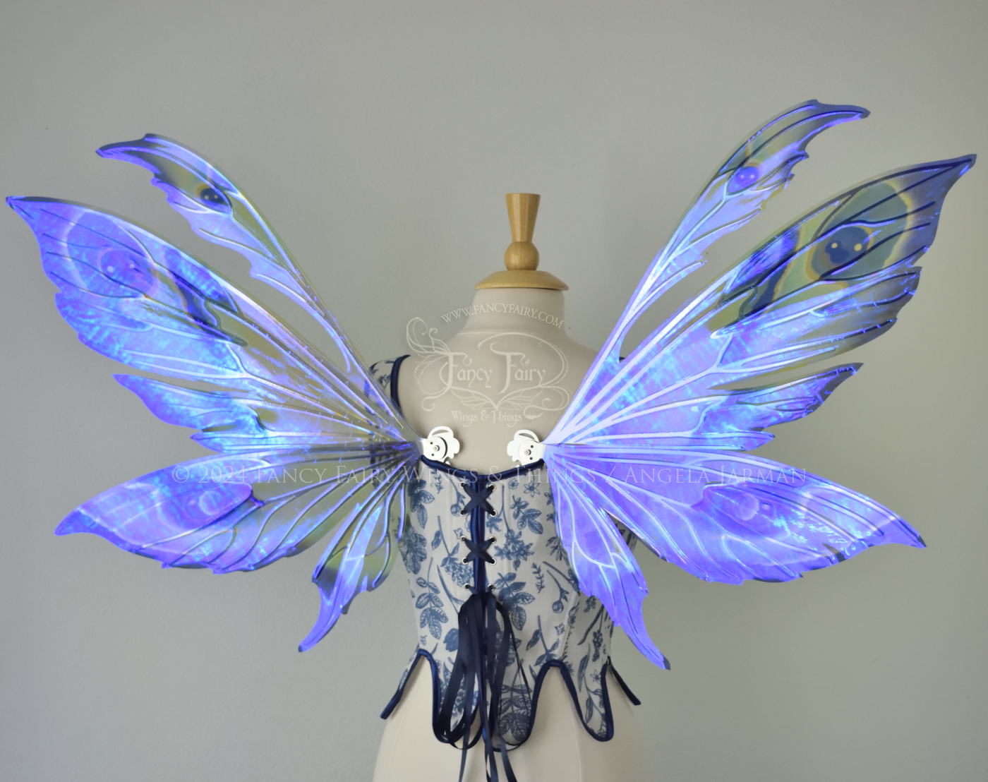 Large iridescent blue & purple painted fairy wings with pointed tips & antennae, with silver veins, worn on a dress form, back view.