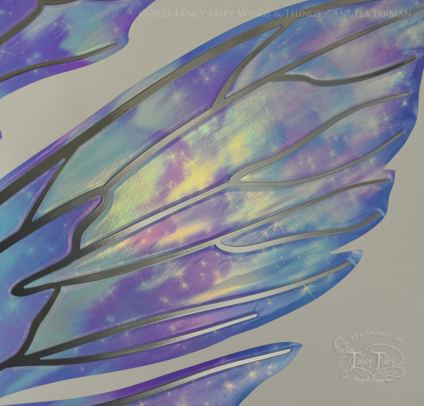 Close-up of upper right panel of iridescent fairy wings with pointed tips & antennae, painted with auroras & stars in pinks, purples & blues, with silver veins