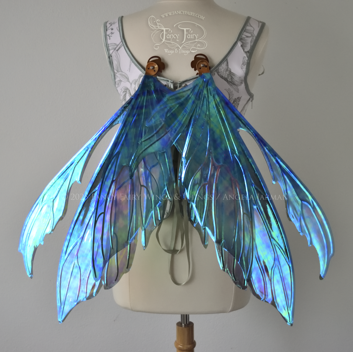 Large iridescent fairy wings with antennae in shades of teal with pink & lavender accents & copper veins, worn on a dress form, in resting position, back view