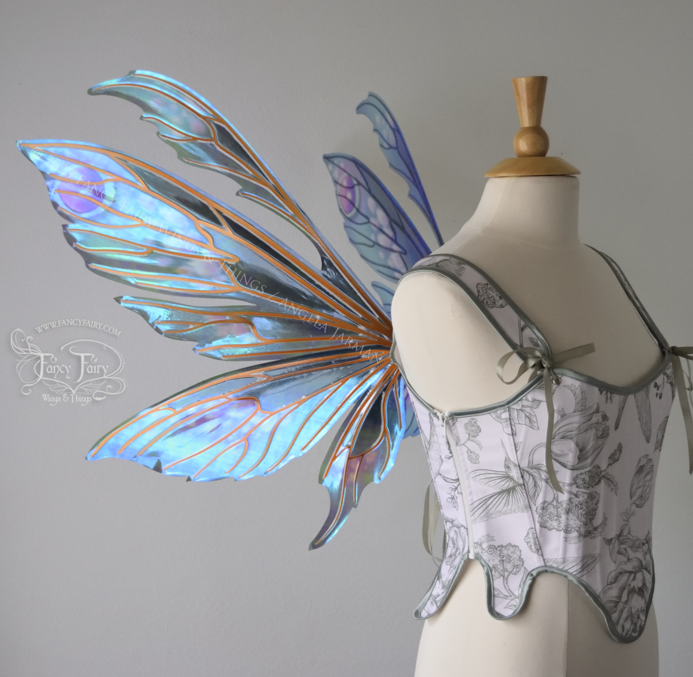 Large iridescent fairy wings with antennae in shades of teal with pink & lavender accents & copper veins, worn on a dress form, left side view