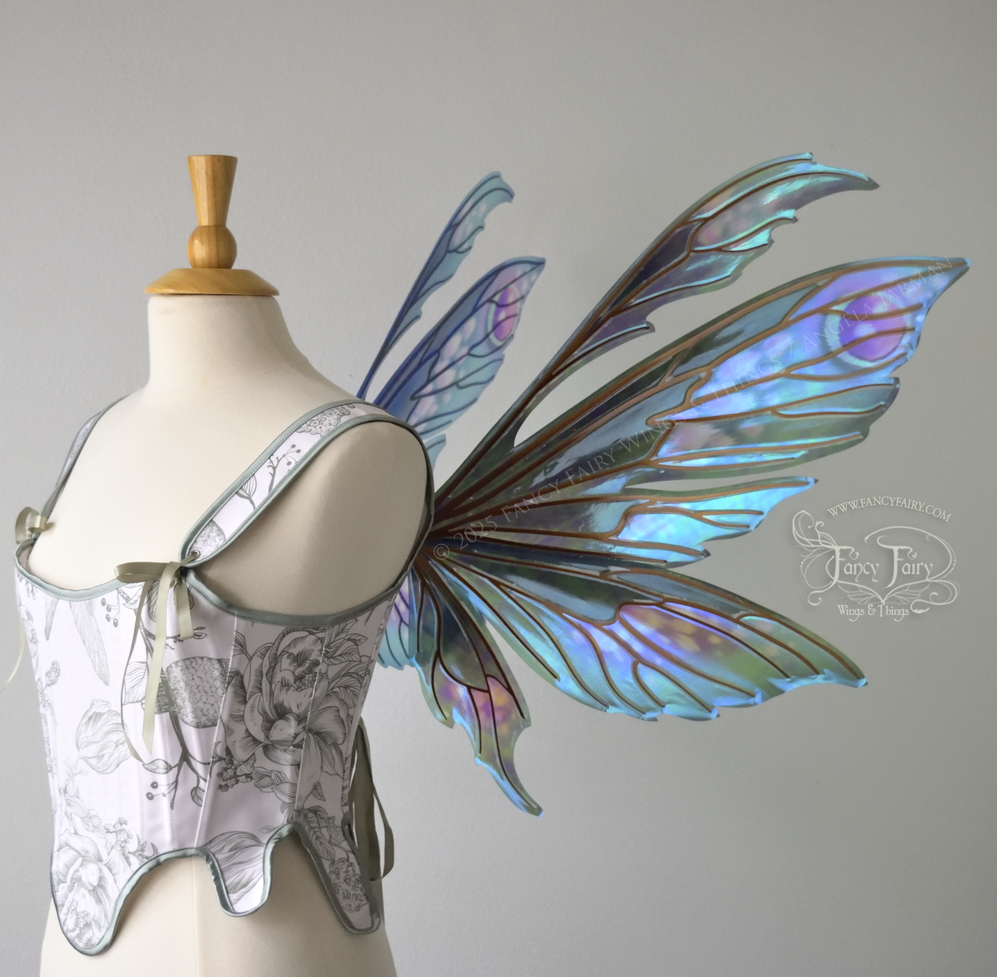 Large iridescent fairy wings with antennae in shades of teal with pink & lavender accents & copper veins, worn on a dress form, right side view