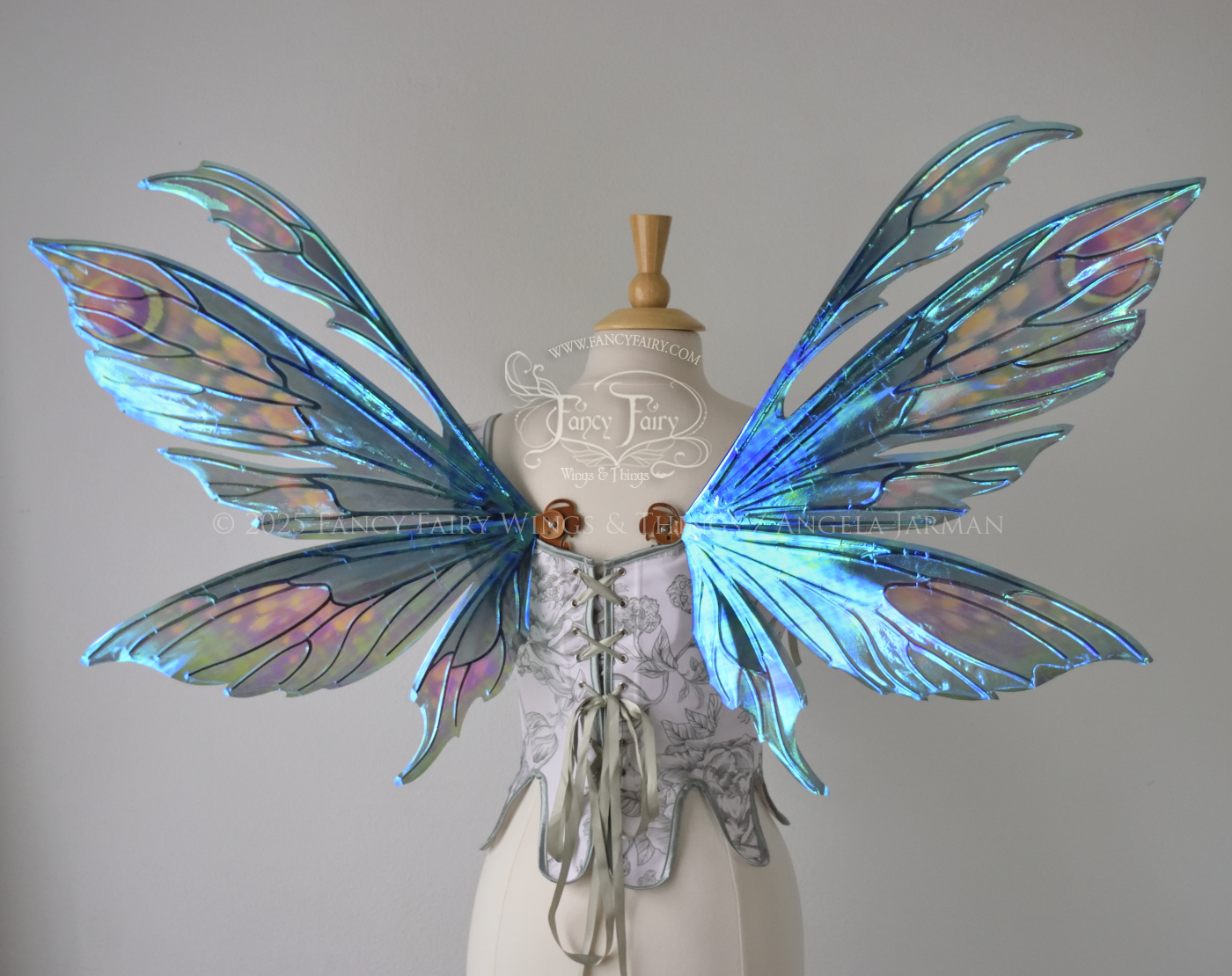 Large iridescent fairy wings with antennae in shades of teal with pink & lavender accents & copper veins, worn on a dress form, back view