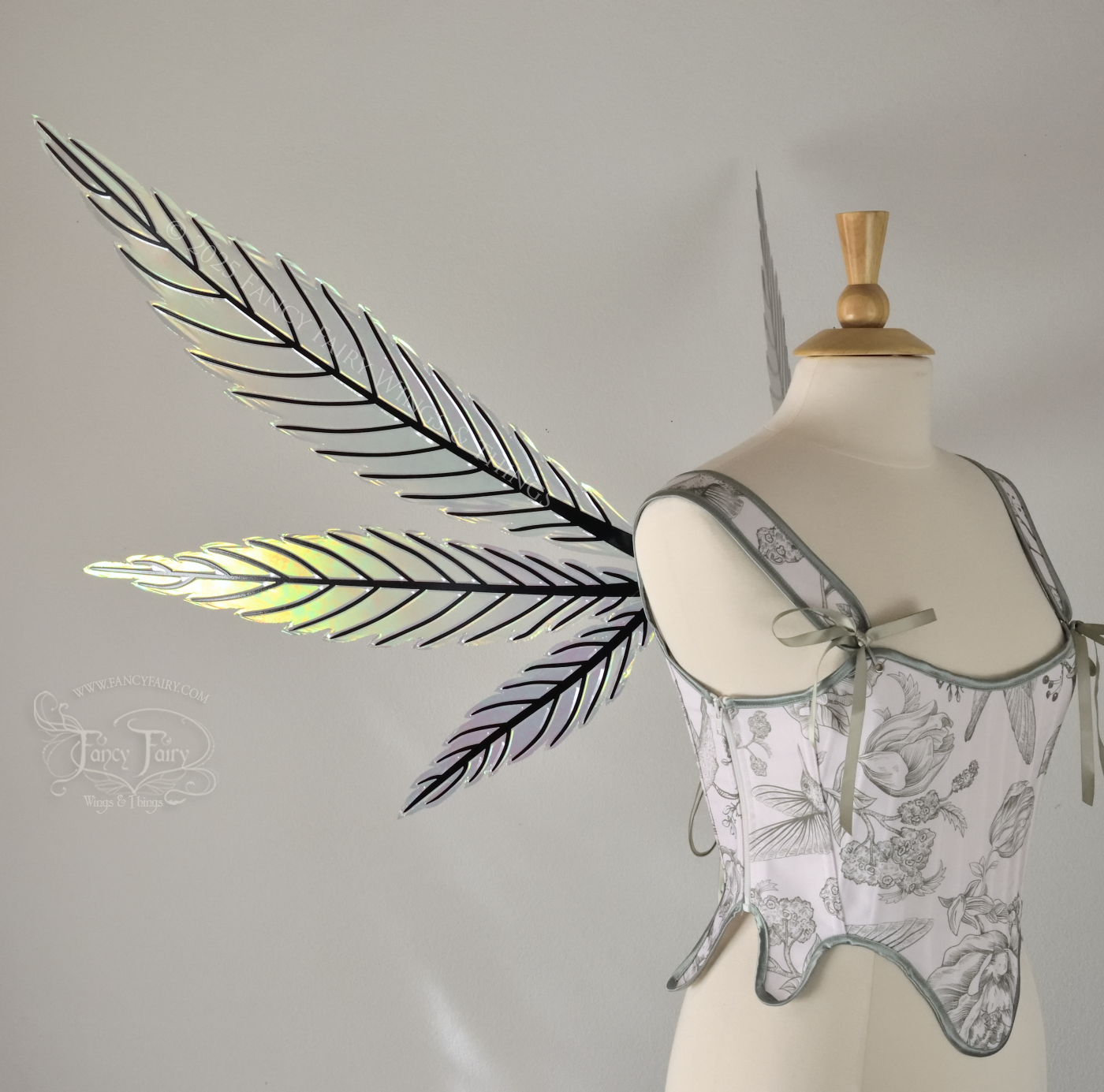 Green iridescent fairy wings styled after hemp leaves with black veins, worn on a dress form, left side view