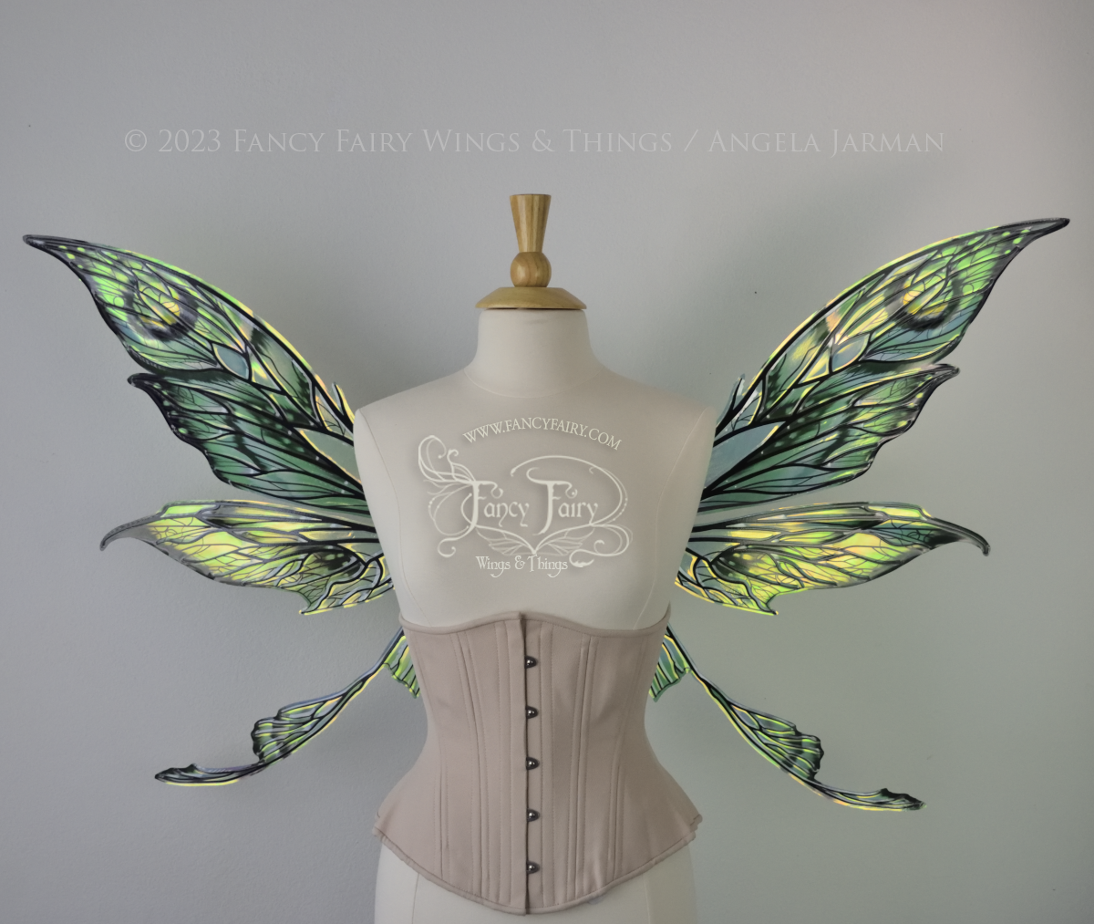 Front view of large green, gold & black painted iridescent fairy wings with black veins. Upper panels are elongated with pointed tips, a ‘tail’, lots of vein detail