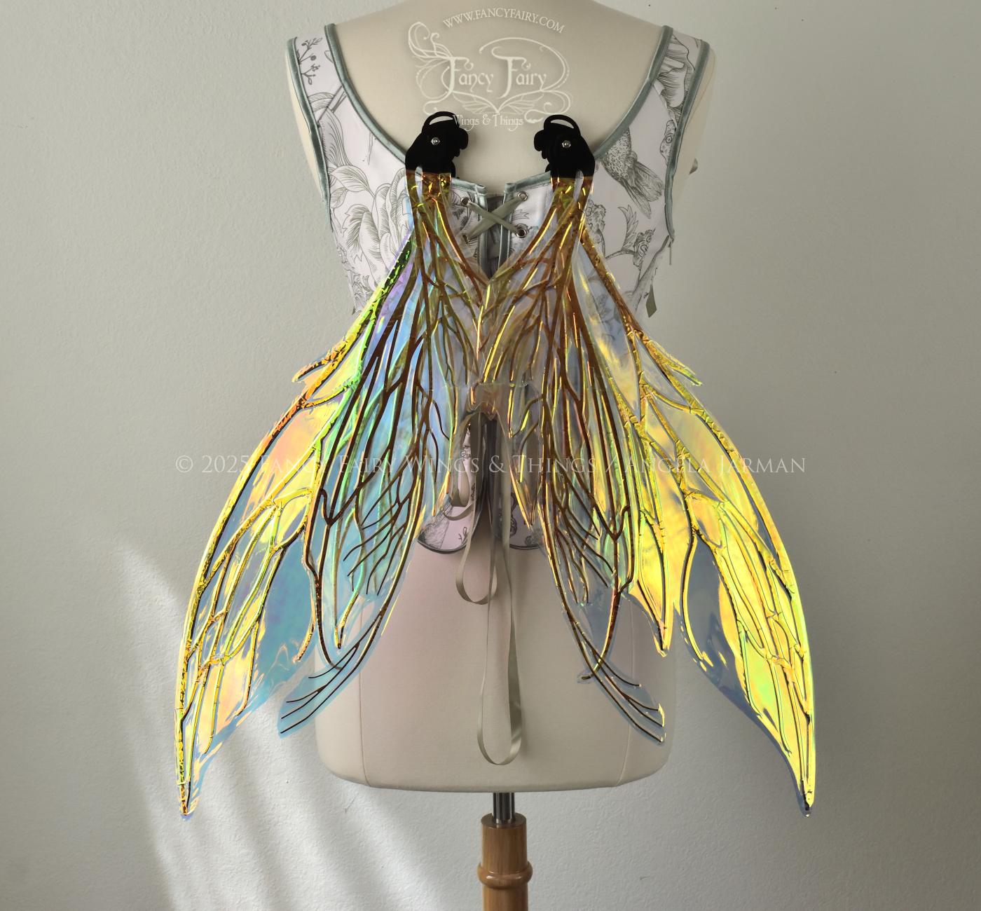 Transparent & iridescent fairy wings reflecting yellow, orange & green with black veins, worn on a dress form, back view in resting position