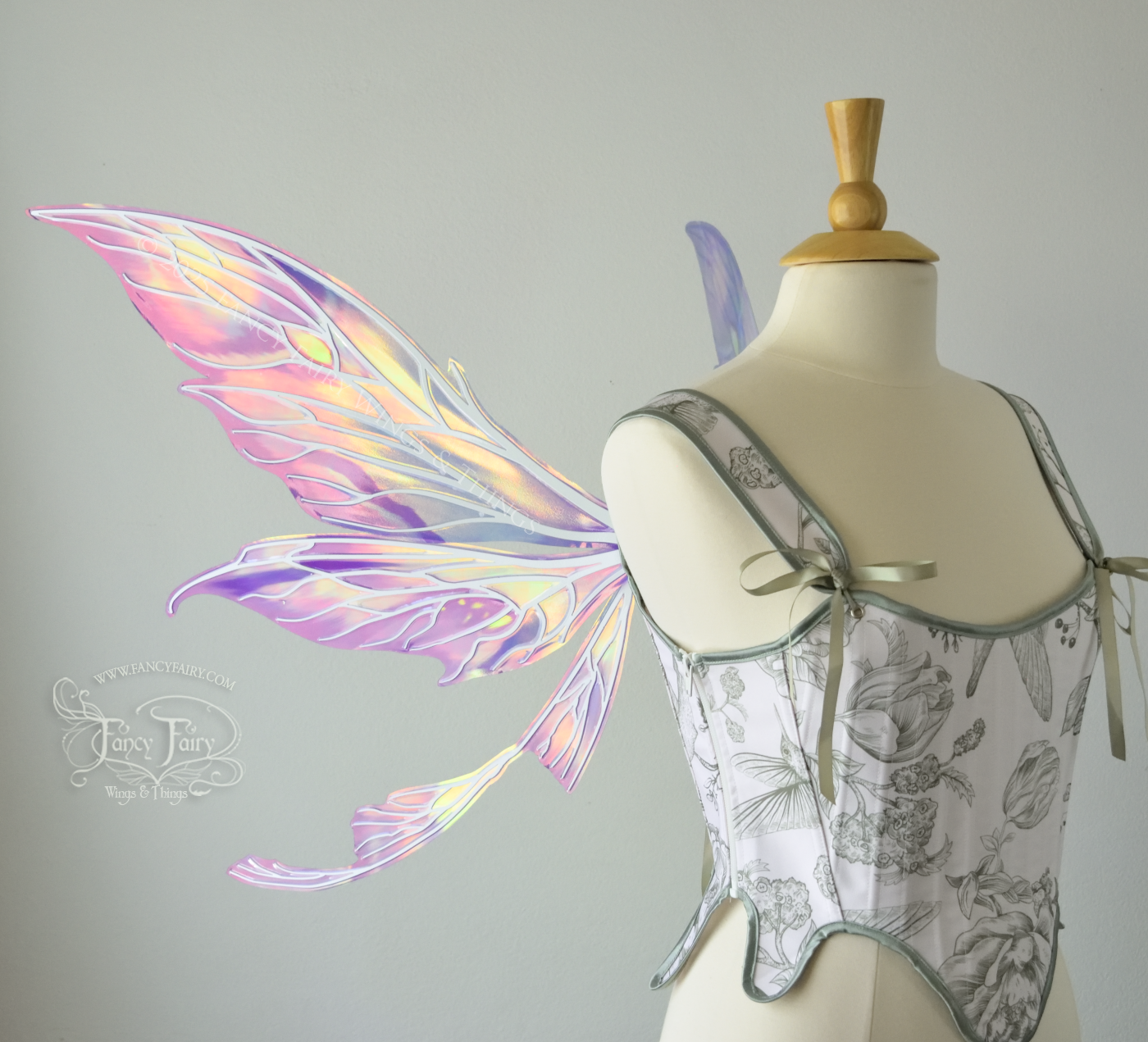 Large painted iridescent fairy wings in berry colors with white veins. Upper panels are elongated with pointed tips, curved ‘tail’, worn on a dress form, left side view