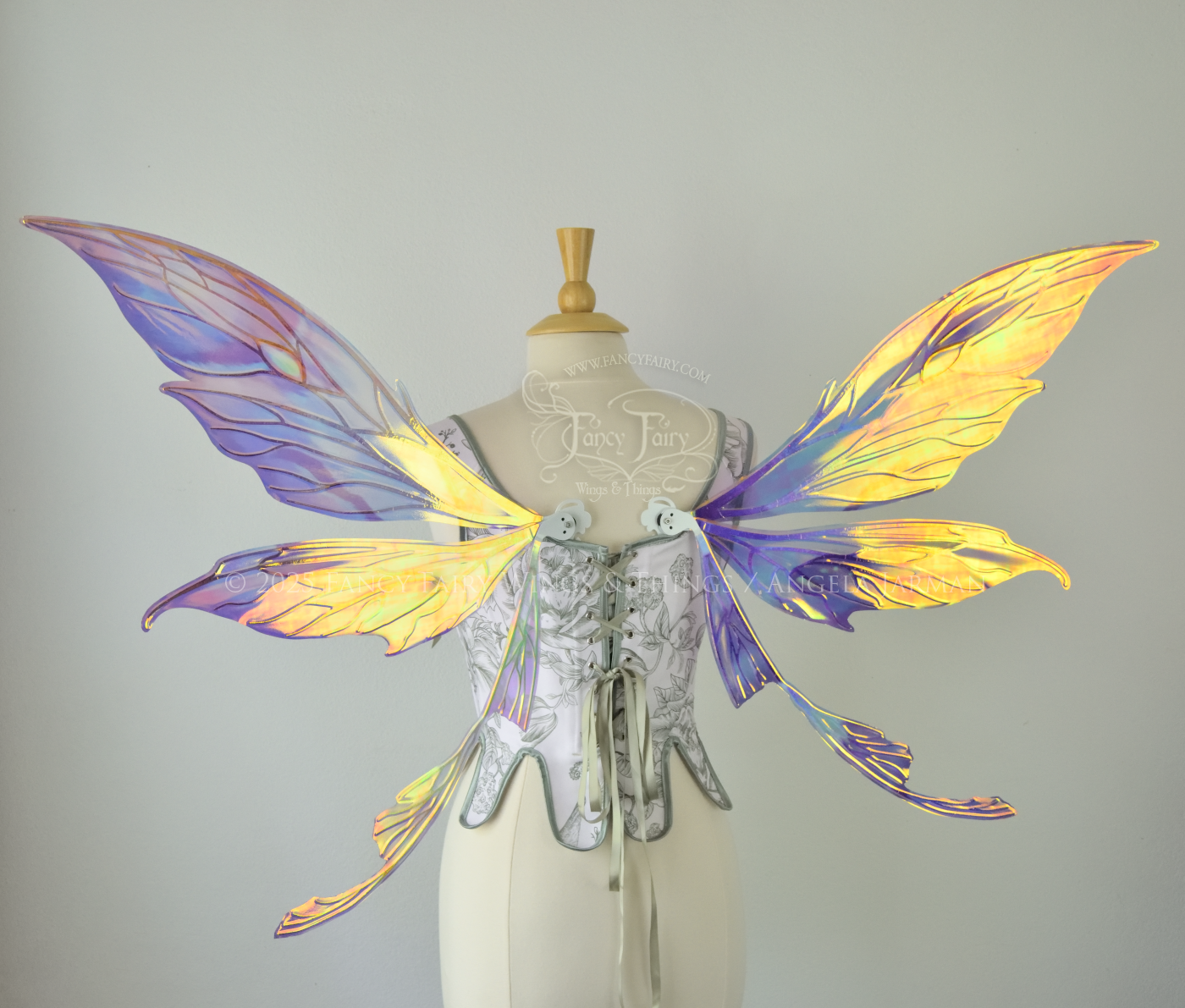 Large painted iridescent fairy wings in berry colors with white veins. Upper panels are elongated with pointed tips, curved ‘tail’, worn on a dress form, back view