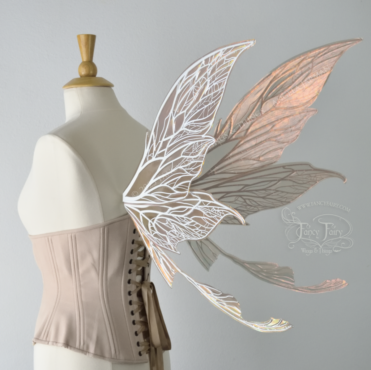 Back 3/4 view of a dress form wearing an underbust corset and large Rose Gold iridescent fairy wings with tails & detailed white veins