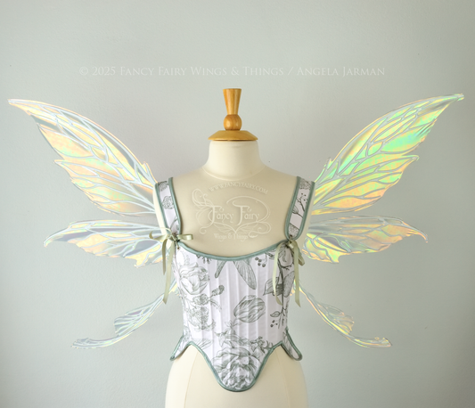 Large iridescent green fairy wings with white veins. Upper panels are elongated with pointed tips, curved ‘tail’, worn on a dress form, front view