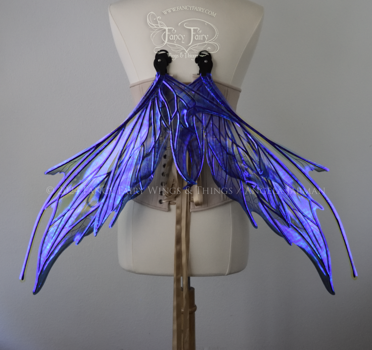 Back view of large spikey blue painted iridescent fairy wings with antennae along the top & black detailed veins, displayed on dress form in resting position. 