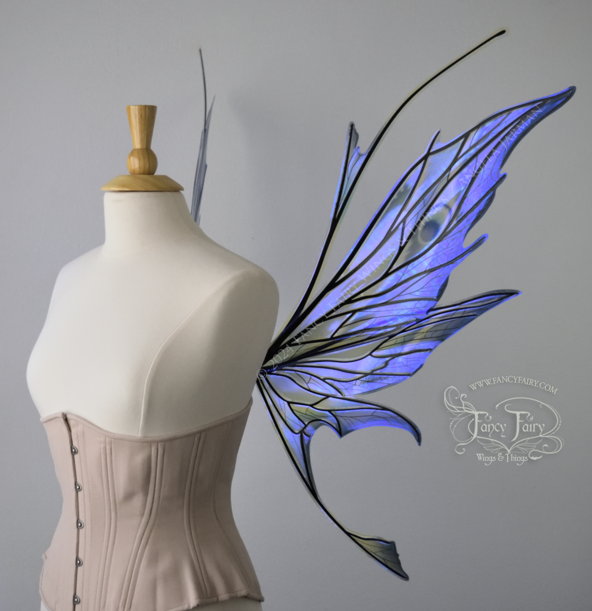 Right side view of large spikey blue painted iridescent fairy wings with antennae along the top & black detailed veins, displayed on dress form. 