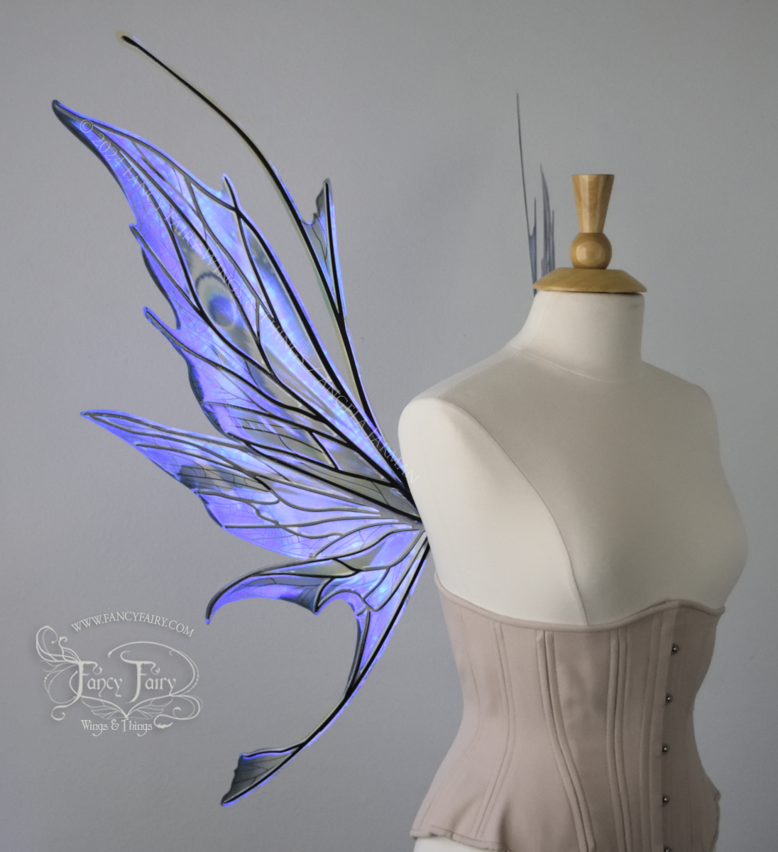 Left side view of large spikey blue painted iridescent fairy wings with antennae along the top & black detailed veins, displayed on dress form. 