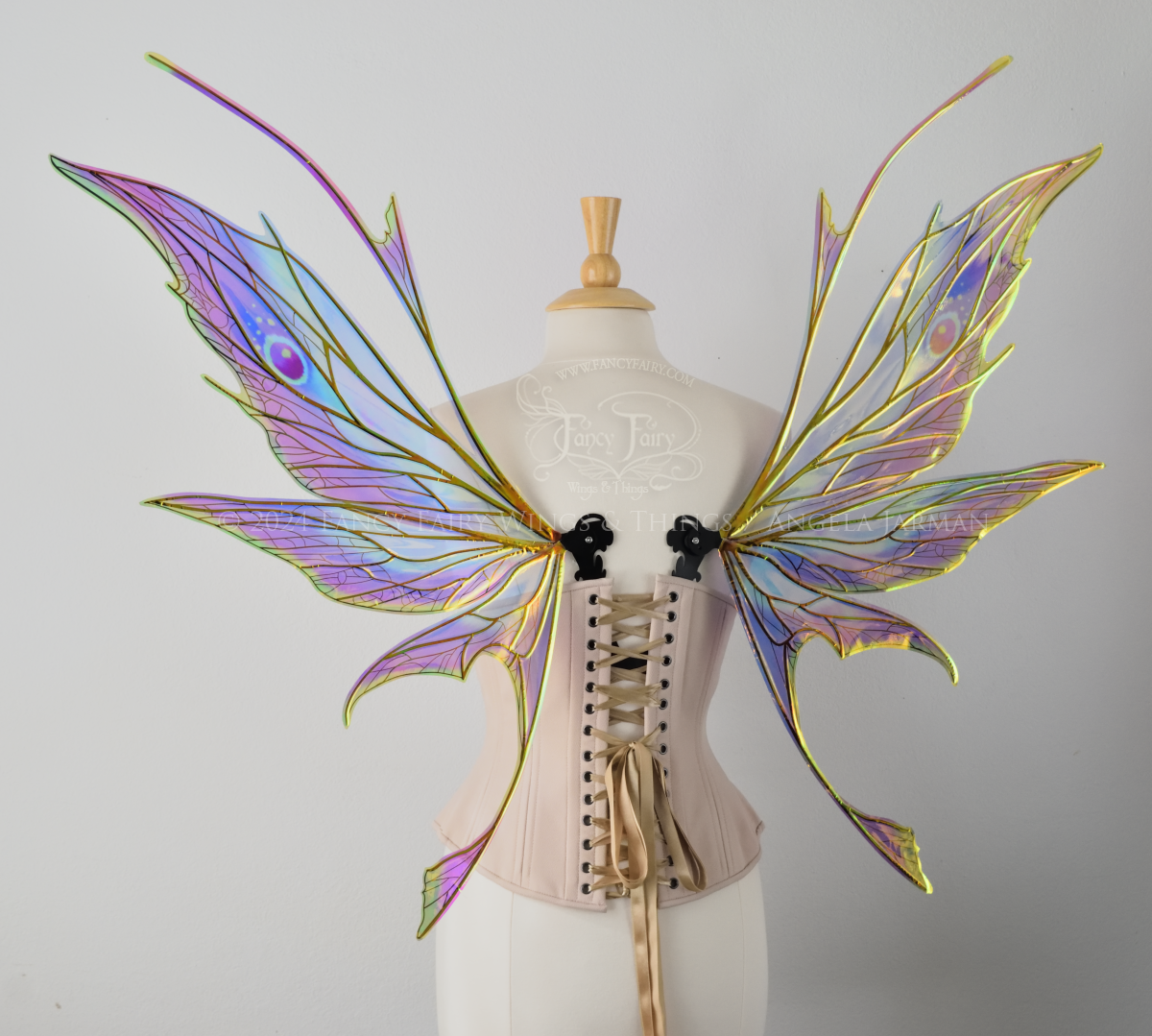 Back view of a dress form wearing an underbust corset & large rainbow iridescent fairy wings featuring antennae along the top. Upper panels come to a point, bottom panels have tails. Spikey, detailed black veins