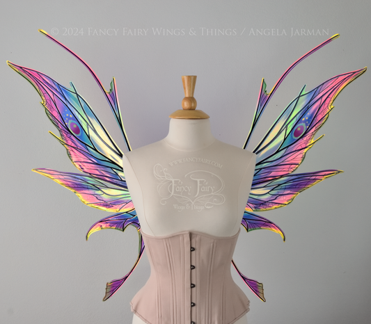 Front view of a dress form wearing an underbust corset & large rainbow iridescent fairy wings featuring antennae along the top. Upper panels come to a point, bottom panels have tails. Spikey, detailed black veins