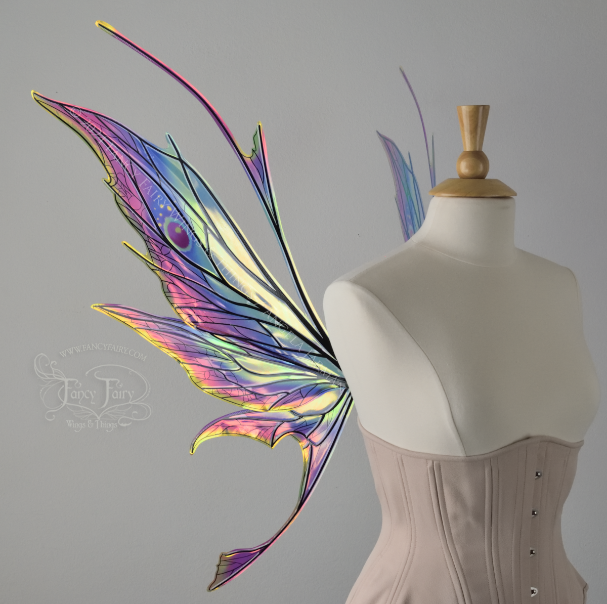 Left side view of a dress form wearing an underbust corset & large rainbow iridescent fairy wings featuring antennae along the top. Upper panels come to a point, bottom panels have tails. Spikey, detailed black veins