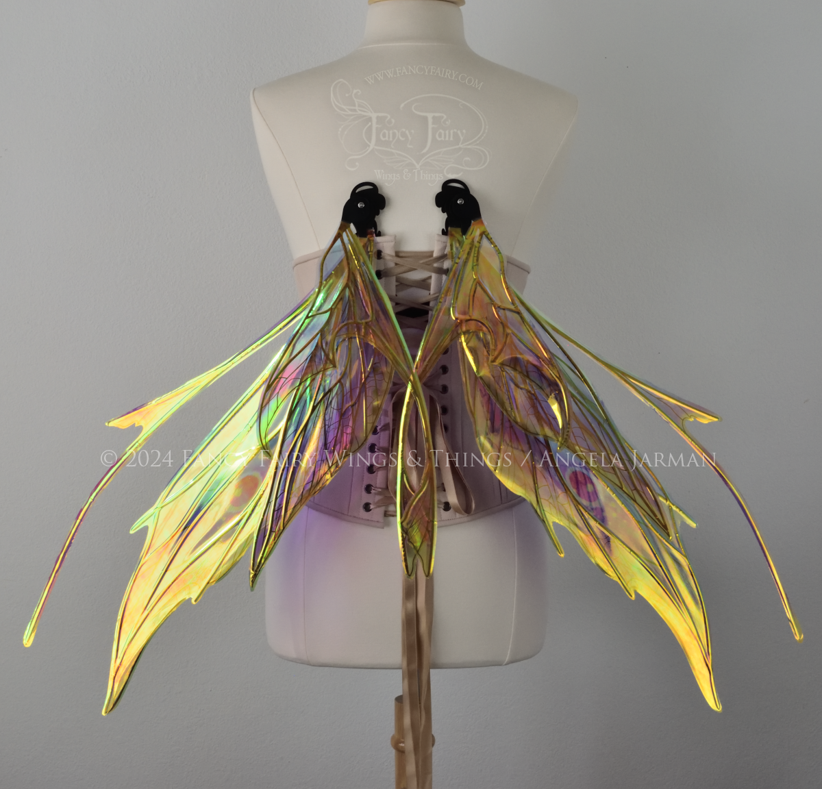 Back view of a dress form wearing an underbust corset & large rainbow iridescent fairy wings in resting position