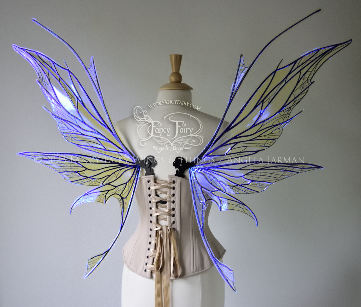 Back view of a dress form wearing an underbust corset & large violet iridescent fairy wings with antennae, black veins, spikey shapes