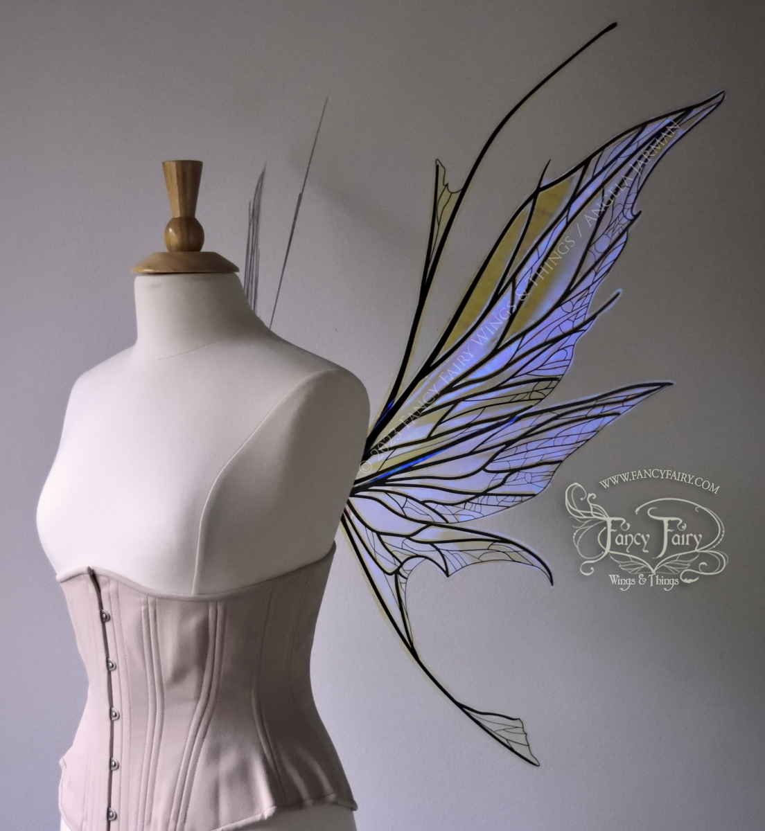 Right side view of a dress form wearing an underbust corset & large violet iridescent fairy wings with antennae, black veins, spikey shapes