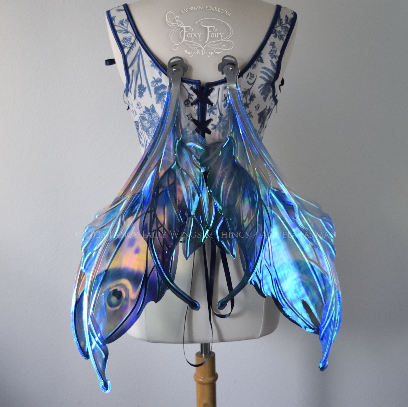 Large blue painted iridescent fairy wings with antennae, silver veins, worn on a dress form, back view, worn on a dress form, in resting position