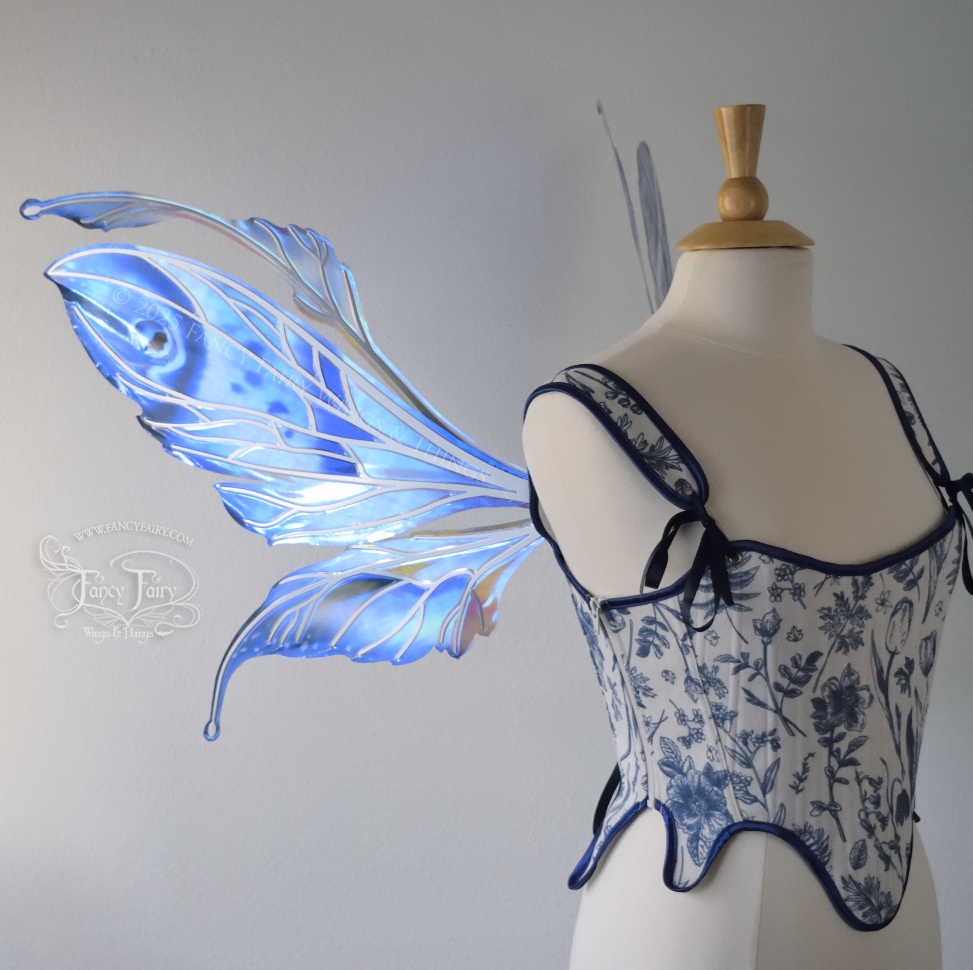 Large blue painted iridescent fairy wings with antennae, silver veins, worn on a dress form, left side view