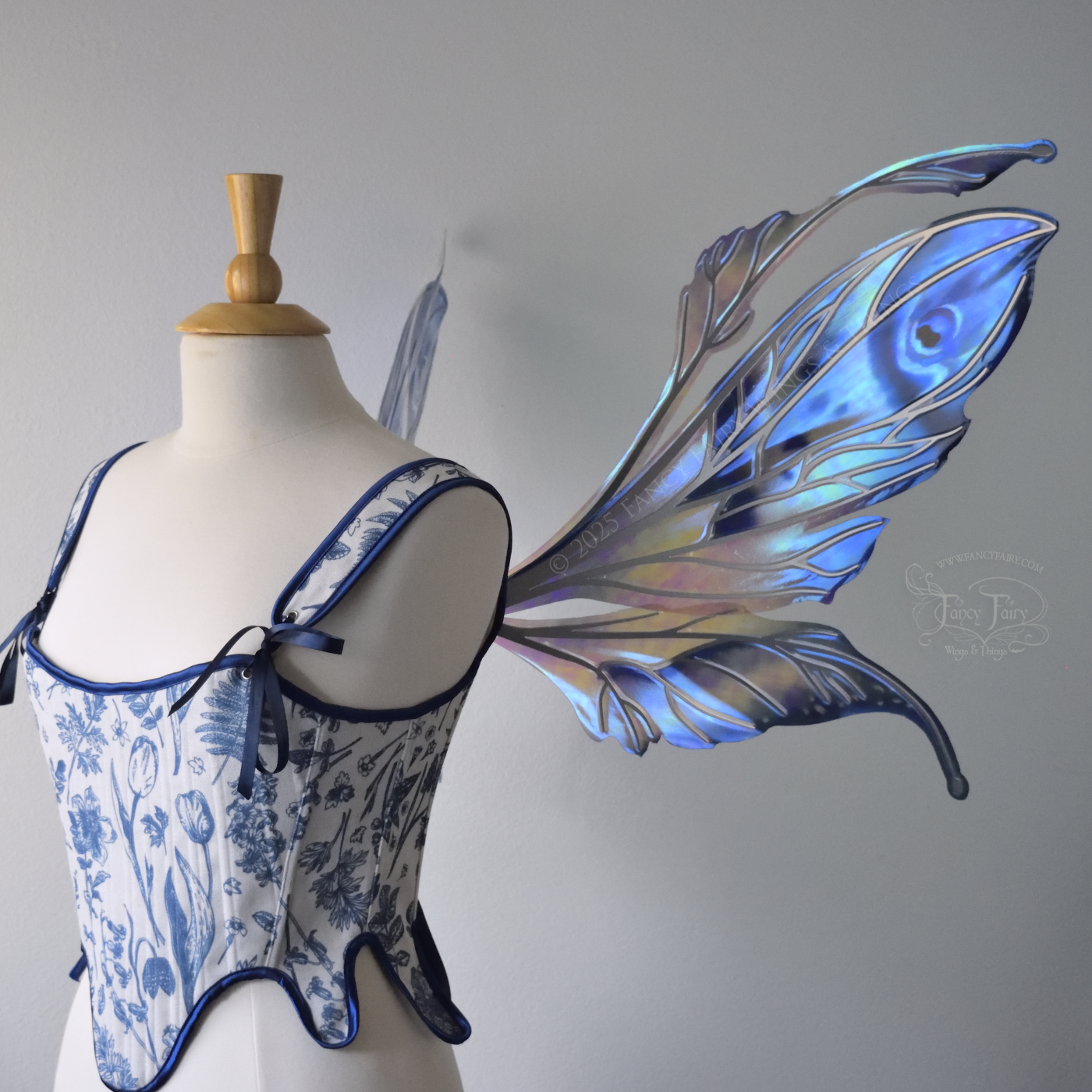 Large blue painted iridescent fairy wings with antennae, silver veins, worn on a dress form, right side view