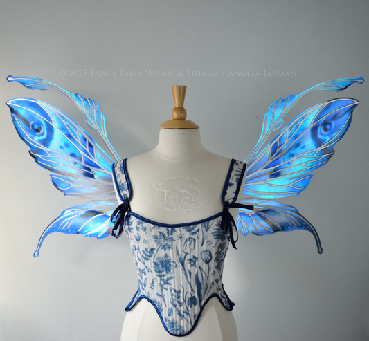Large blue painted iridescent fairy wings with antennae, silver veins, worn on a dress form, front view