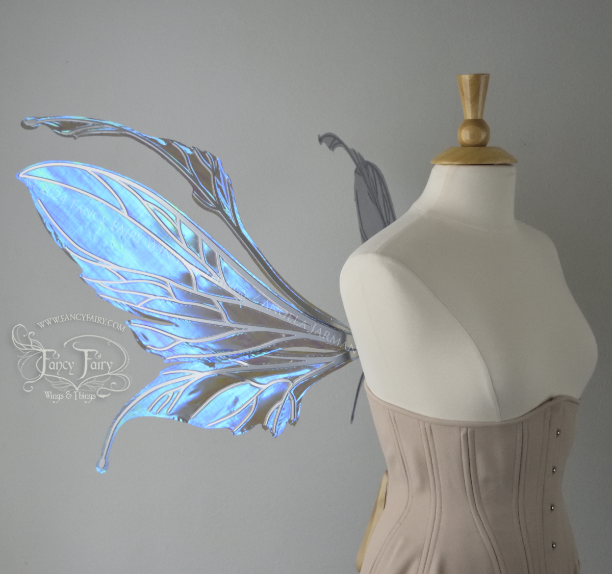 Left side view of a dress form wearing an underbust corset & large iridescent purple fairy wings with antennae. The upper panels are elongated with semi-pointed tips, the lower panels are smaller with downward curved tips, veins are silver.