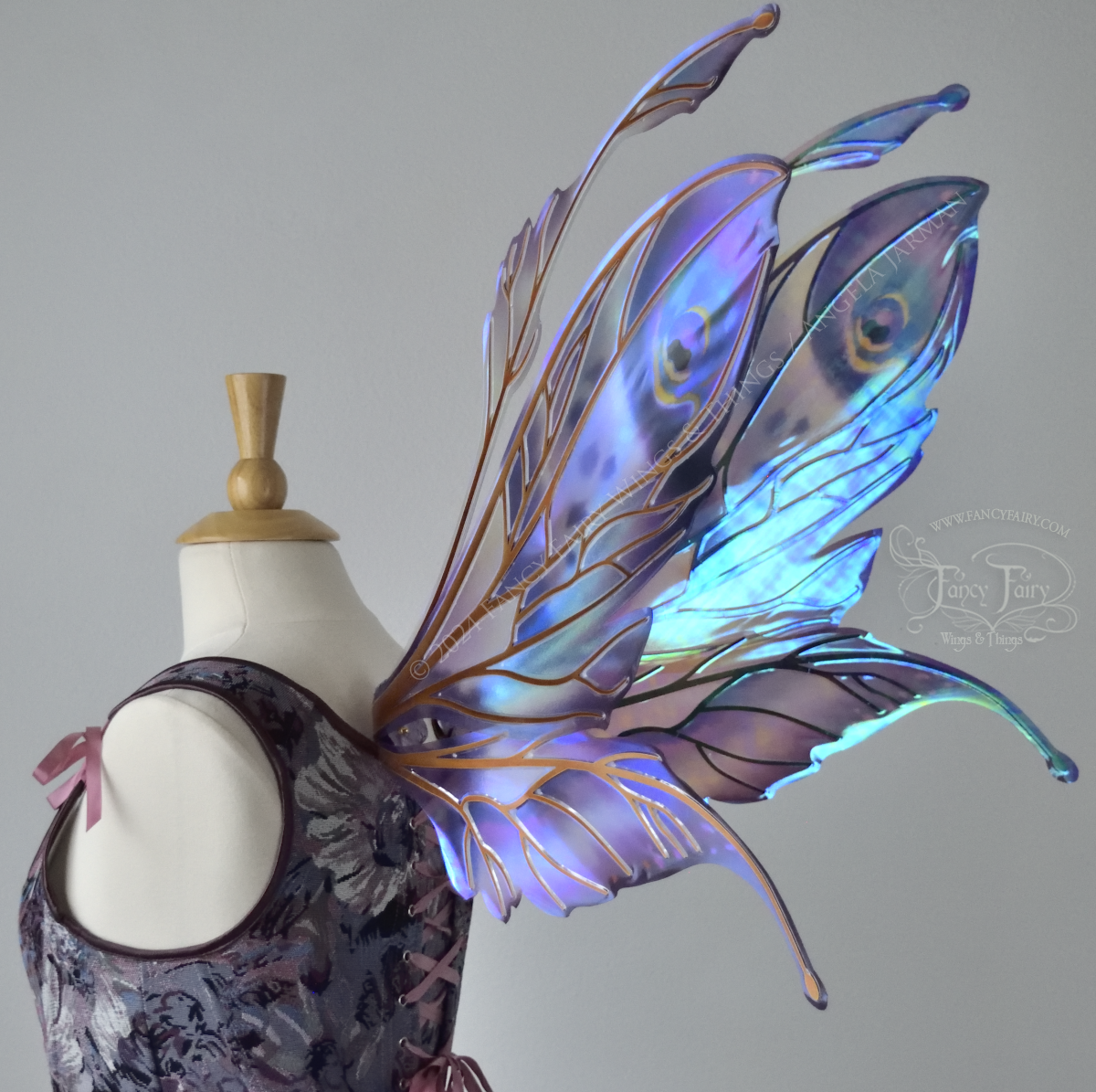 Large mauve, plum and blue iridescent fairy wings with antennae, copper veins, worn with a purple bodice on a dress form, back 3/4 view