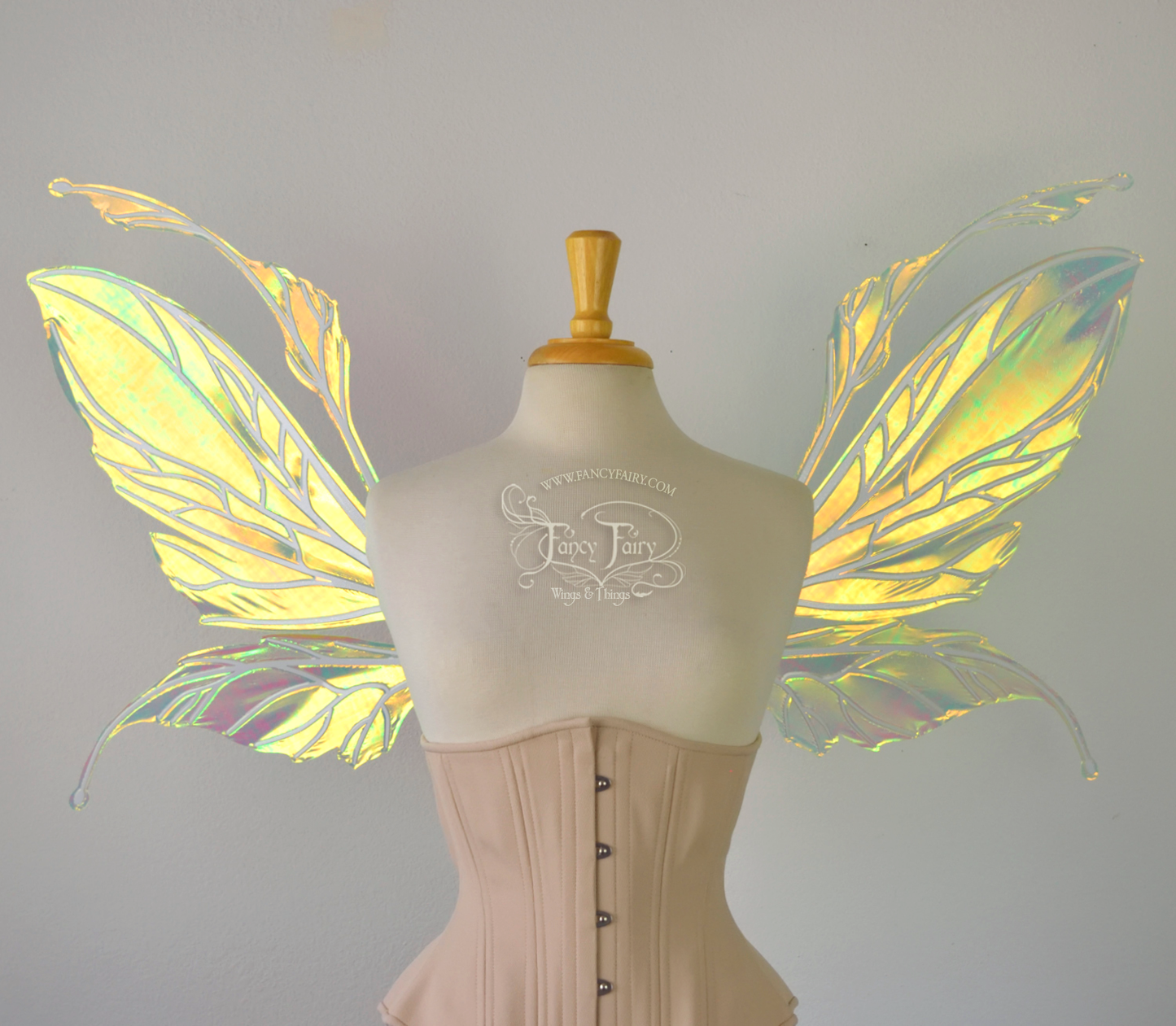 Front view of a dress form wearing an underbust corset and large fairy wings featuring antennae along the top. The upper panels are elongated with semi-pointed tips, the lower panels are smaller with slender tips that curve downward. They are neon yellow iridescent and the veins are white. The background is plain white and my logo and copyright notice are visible.